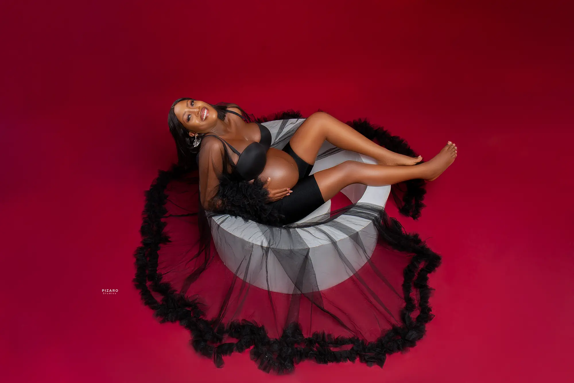 Pizaro Studios maternity session — overhead portrait in black tulle on crimson