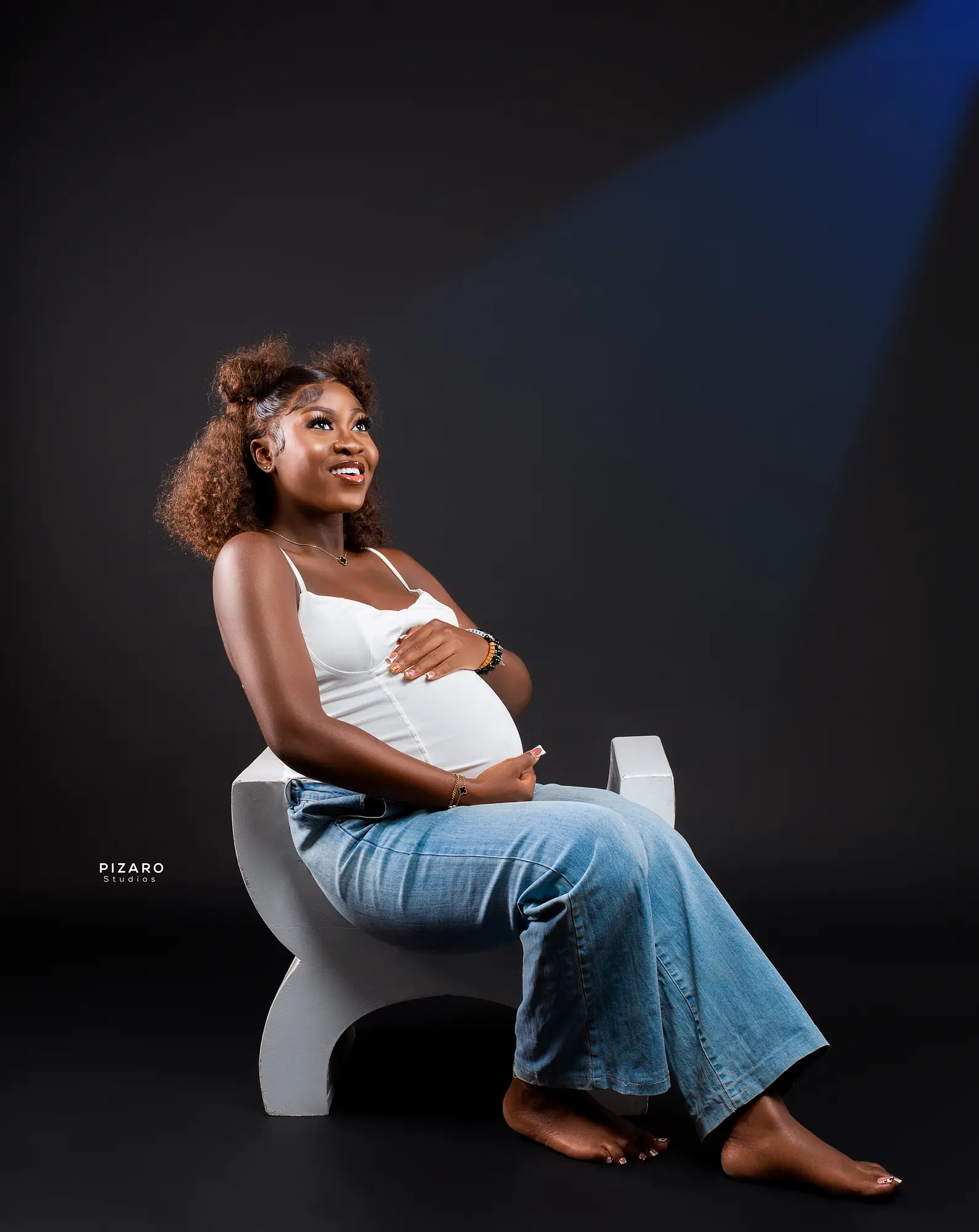 Pizaro Studios maternity session — seated portrait gazing up into a blue beam