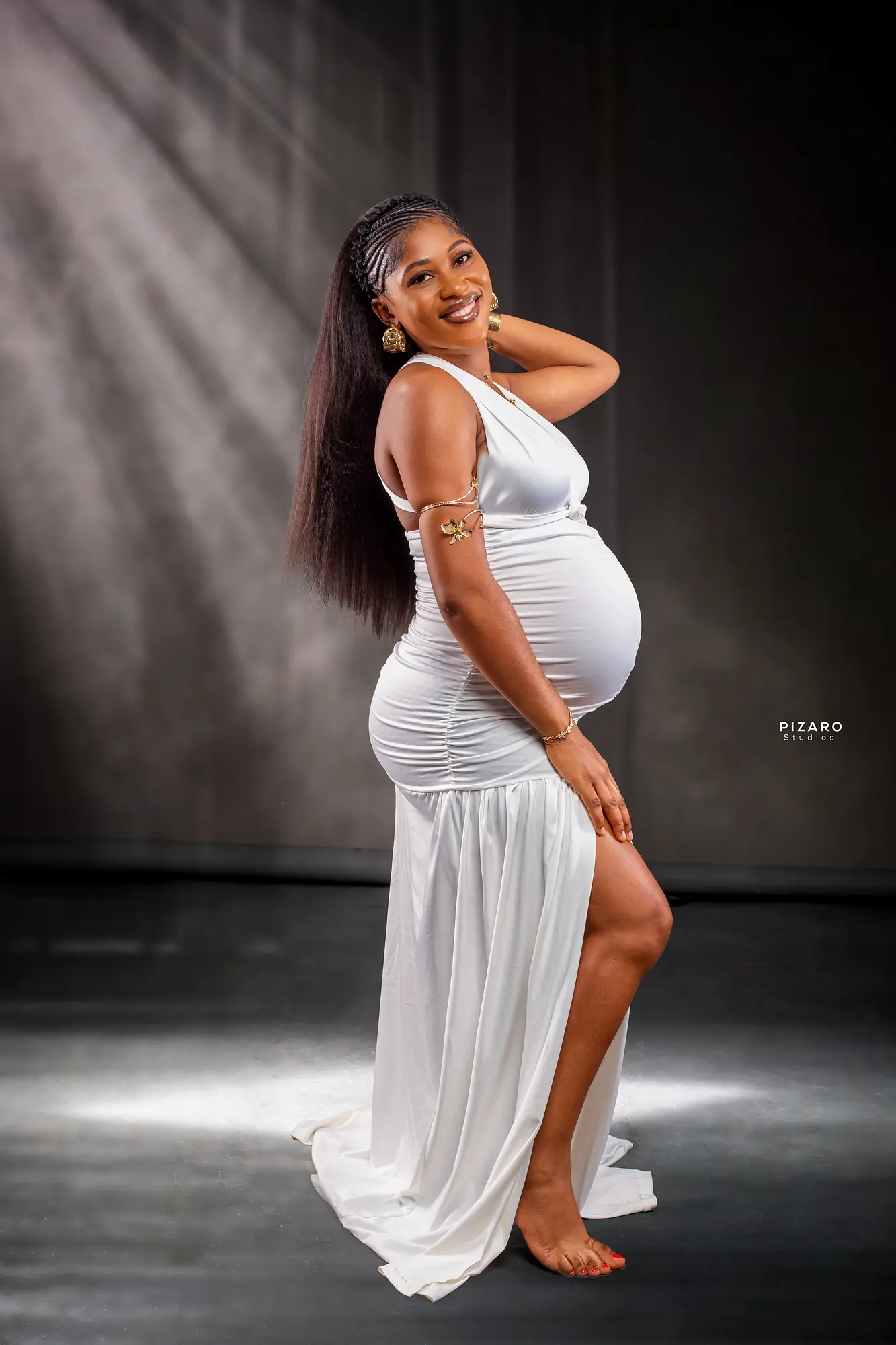 Pizaro Studios maternity session — white gown portrait in dramatic studio light rays