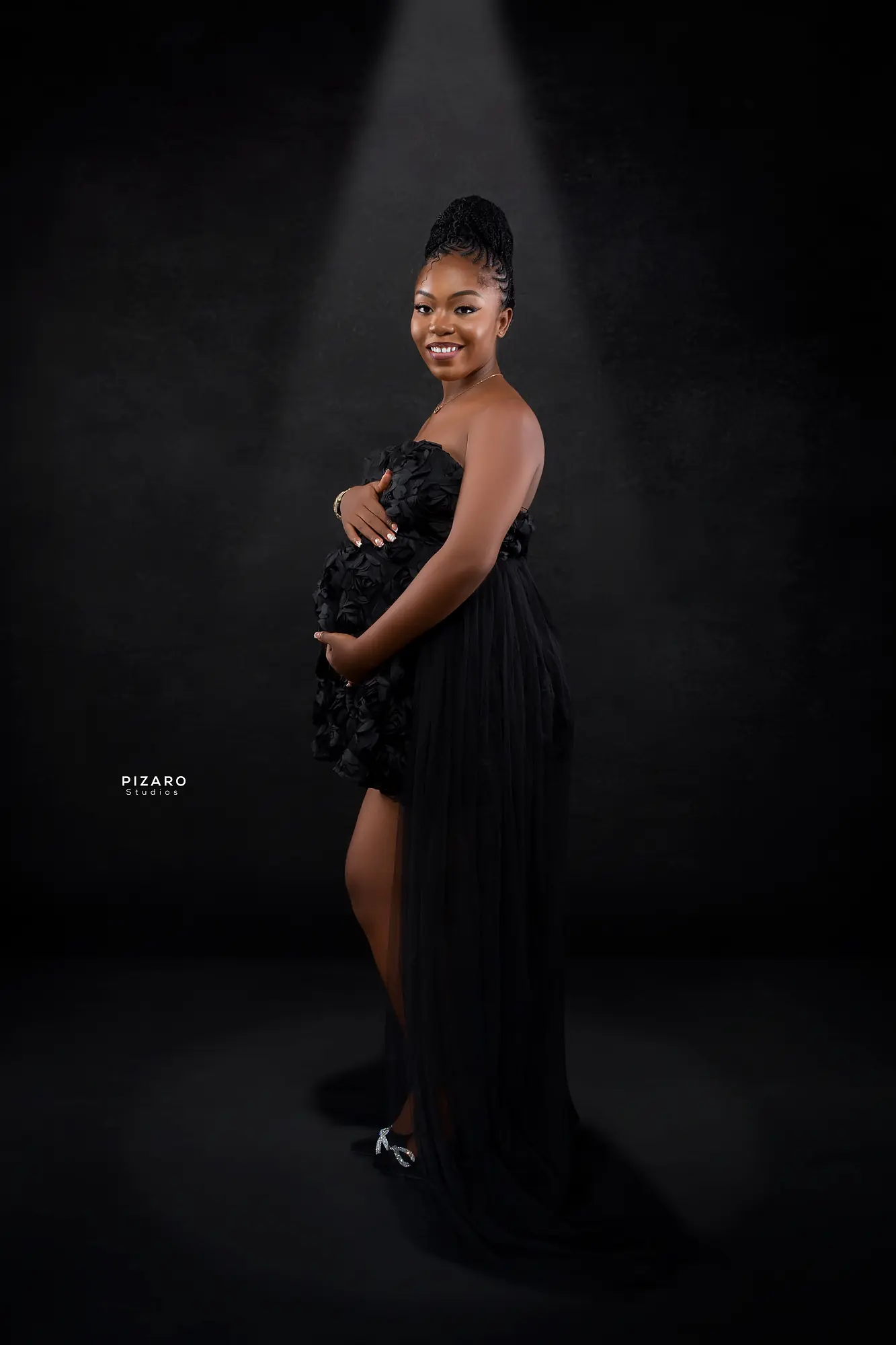 Pizaro Studios maternity session — black rosette gown under a single spotlight